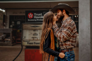 Cowgirl Couple kissing in front of Gasstation